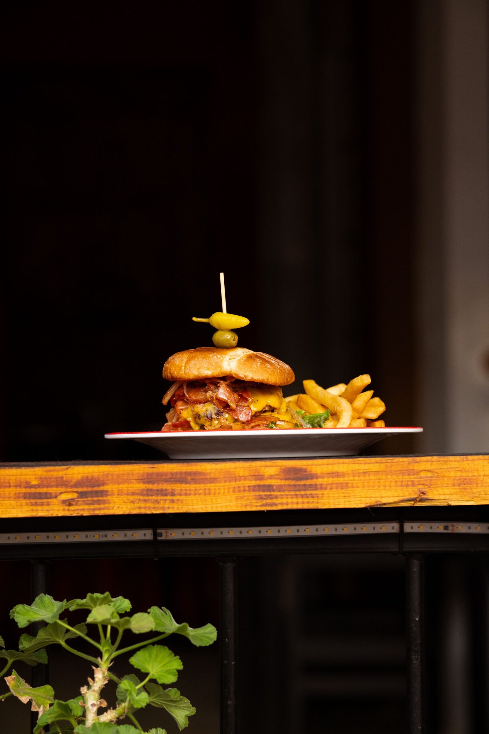 Delicious gourmet burger with fries on a rustic wooden table, perfect for food lovers.